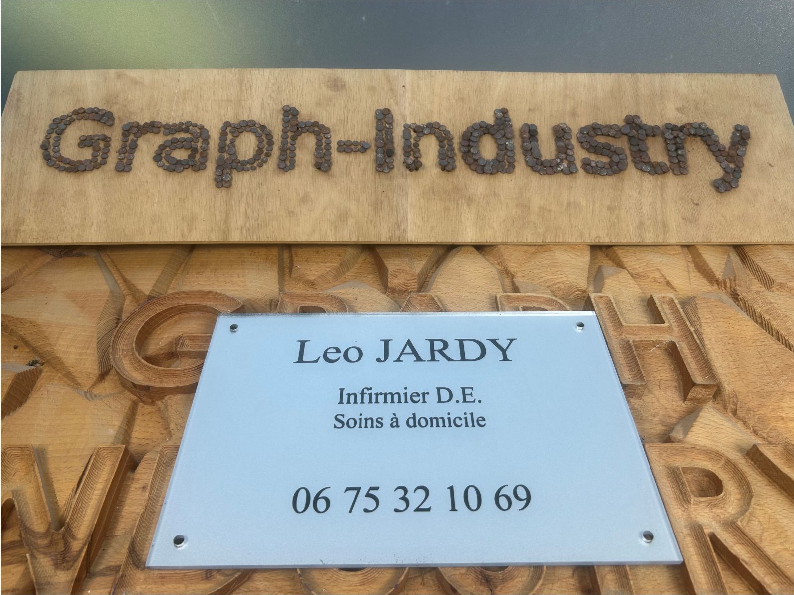 Plaque professionnelle en plexiglas avec gravure et peintures gris métal et noire pour un infirmier.